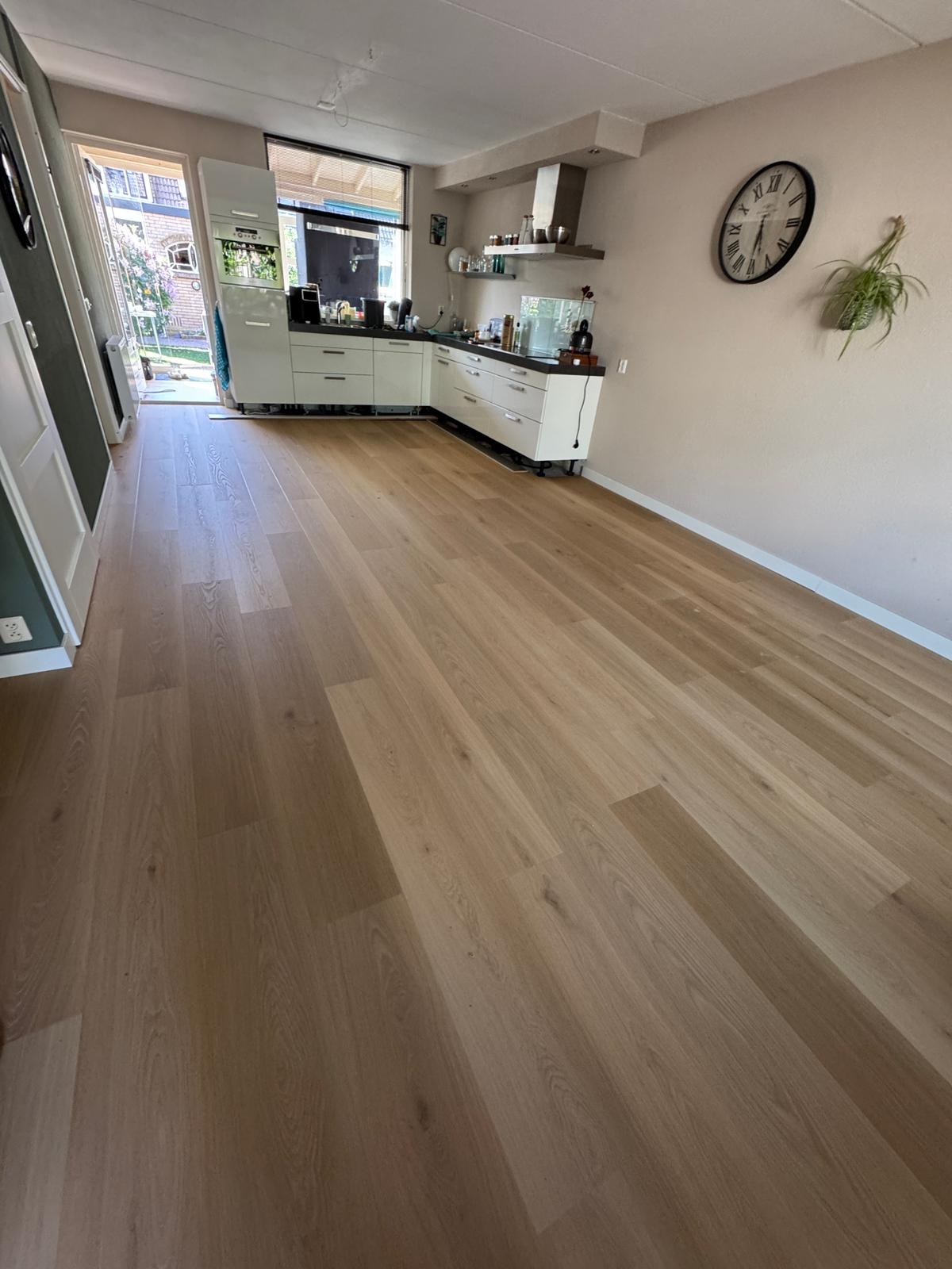 Lichte eiken plankenvloer door een lange woonkamer met keuken
