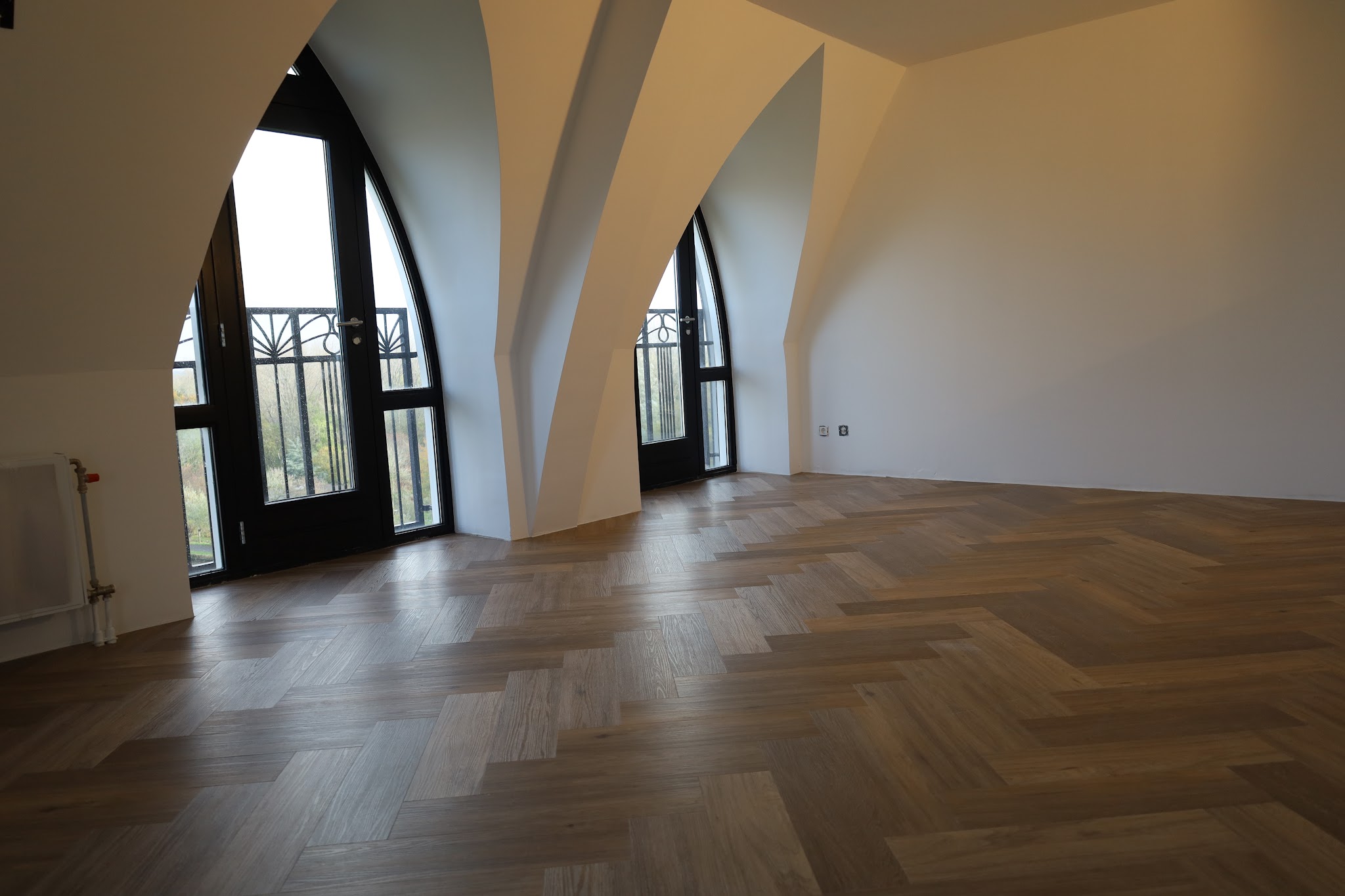 Donkere eiken PVC visgraatvloer in een ruimte met hoge gotische boogramen
