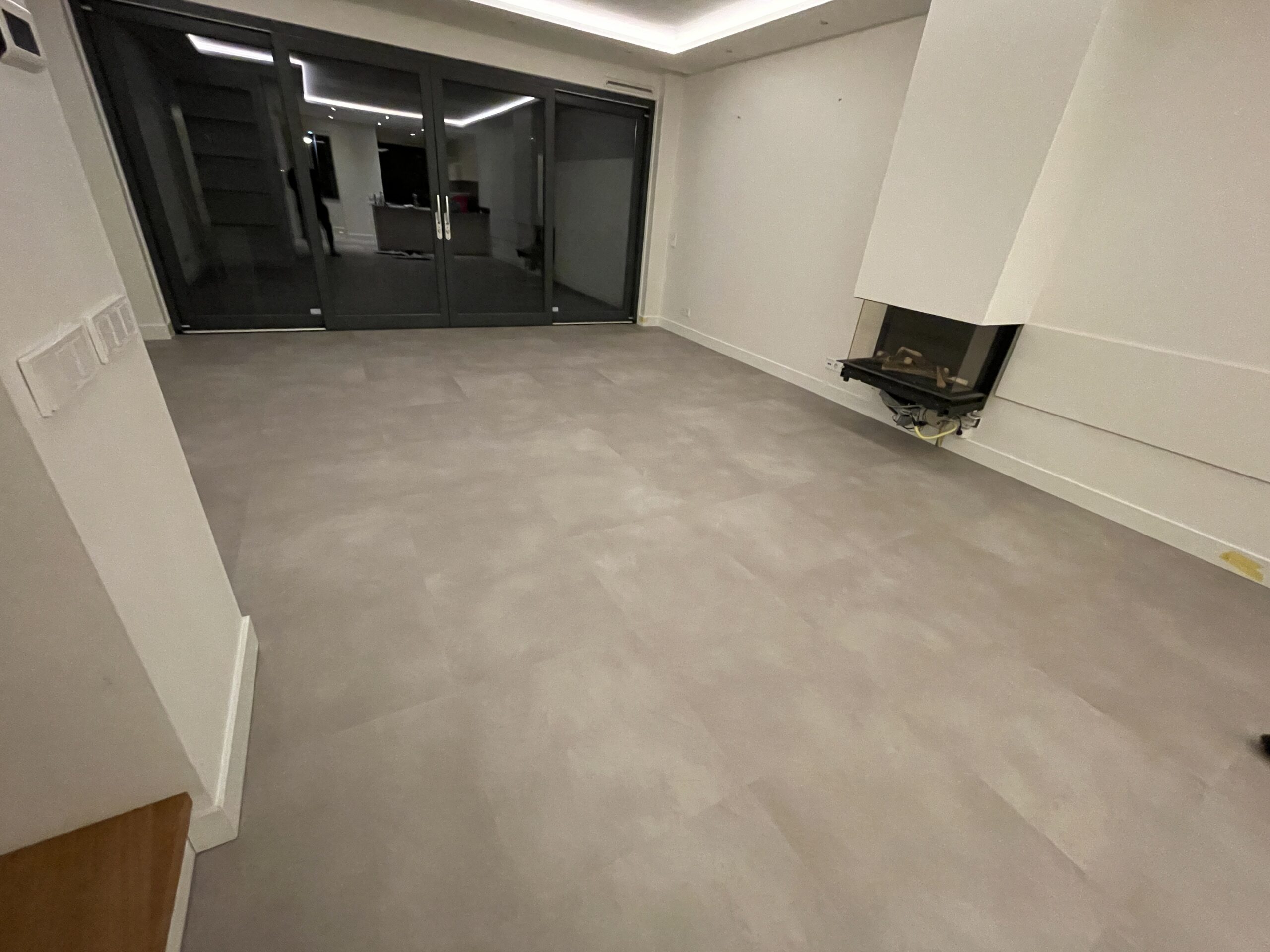Woonkamer met PVC tegels in betonlook en een haard