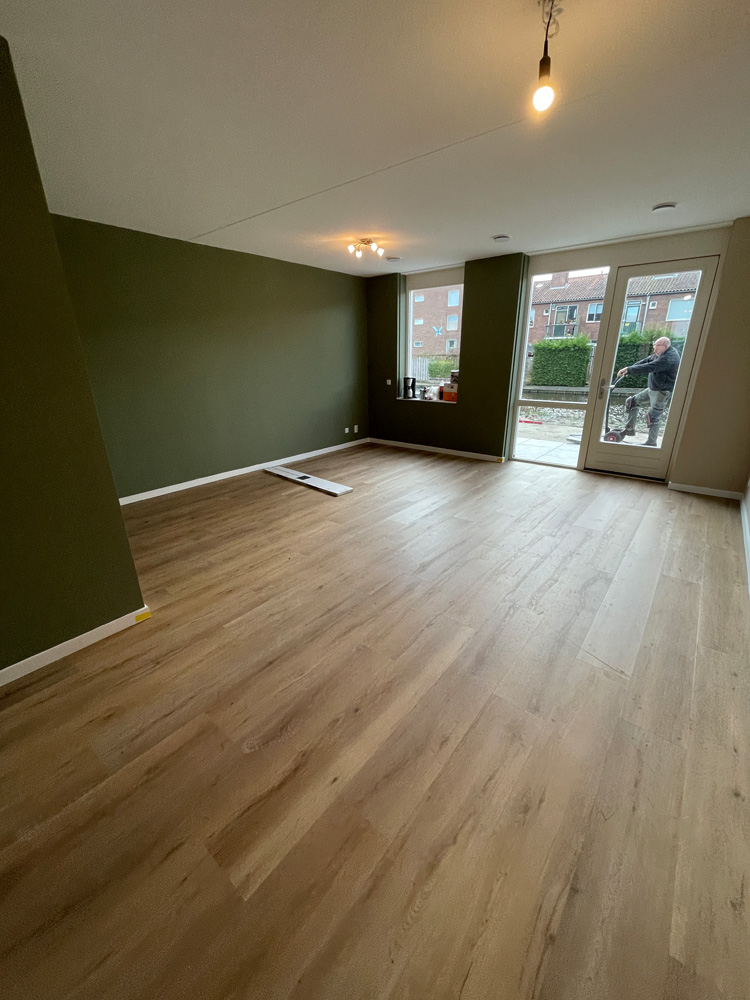 Eikenkleurige PVC plankenvloer in een woonkamer met olijfgroene wand